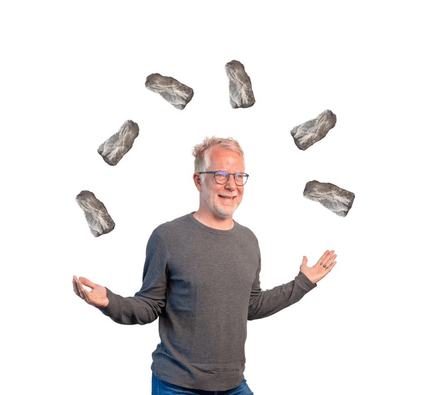 Johannes jongliert lachend mit kleinen Felsen